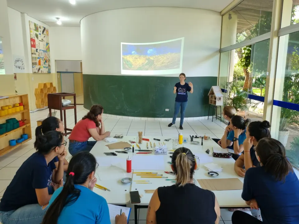 Educadoras sentadas em roda no salão durante um encontro de formação