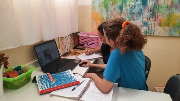 Educadoras estudando diante de um computador portátil