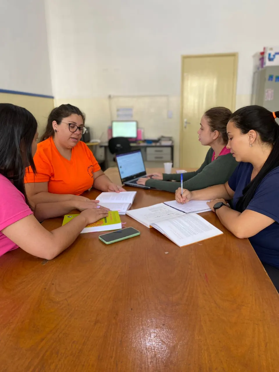 Educadoras reunidas em torno de uma mesa com cadernos e anotações
