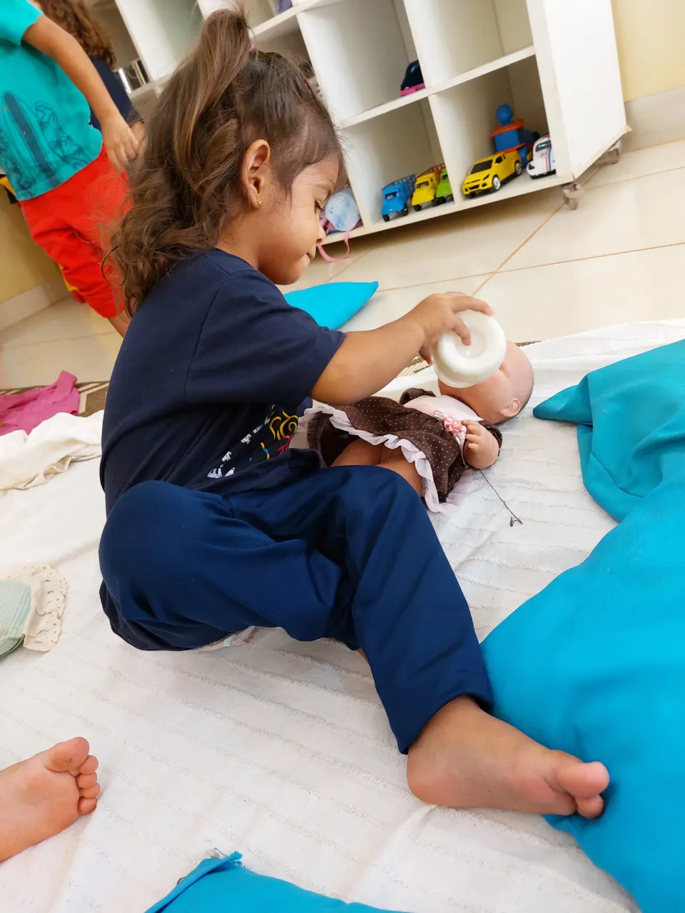 Criança sentada no chão cuidando de uma boneca