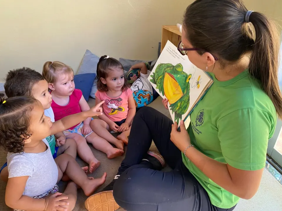 Educadora lendo um livro para um grupo de bebês