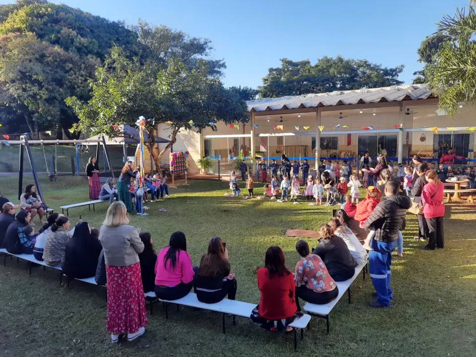 Famílias reunidas no gramado da creche durante um encontro ao ar livre