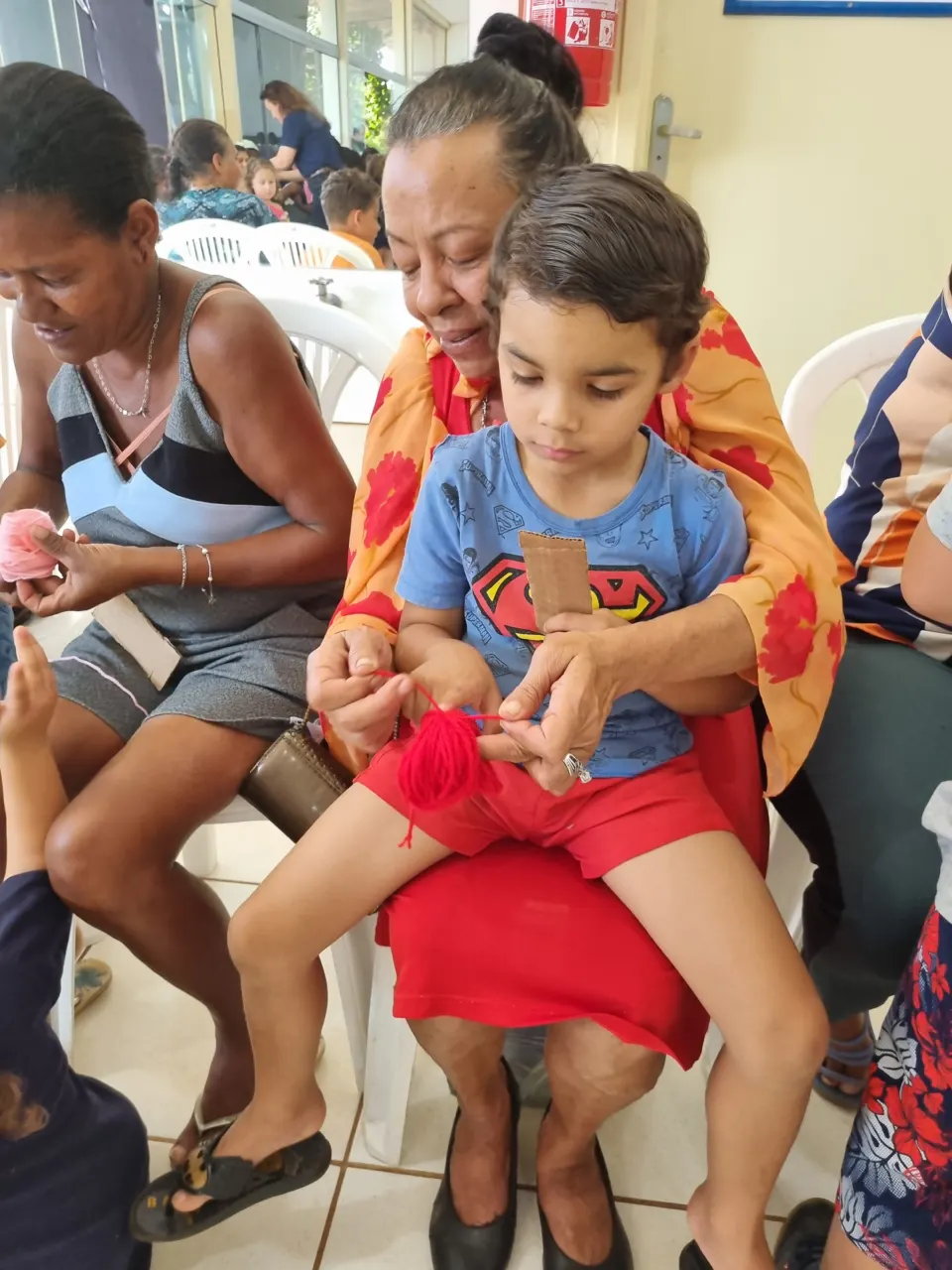 Criança no colo de uma familiar durante uma atividade manual