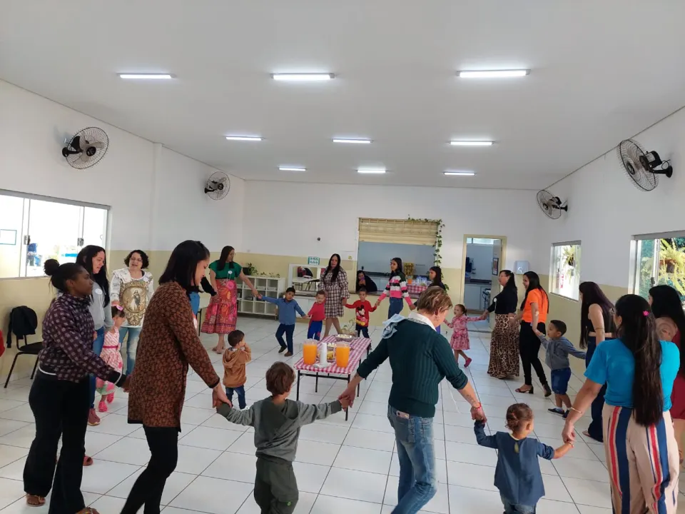 Famílias e crianças de mãos dadas em uma grande roda no salão