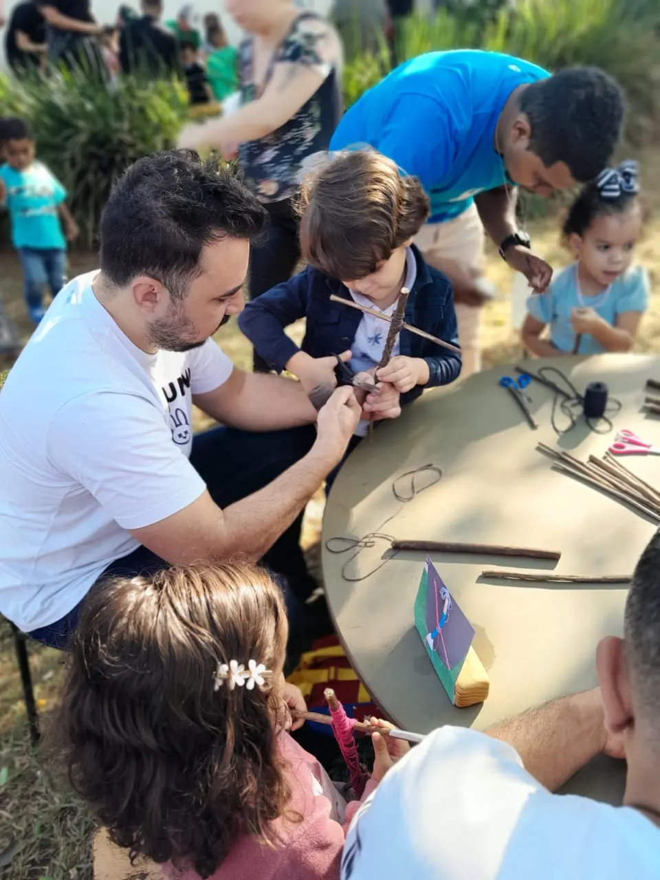 Pais e crianças construindo juntos em uma mesa ao ar livre
