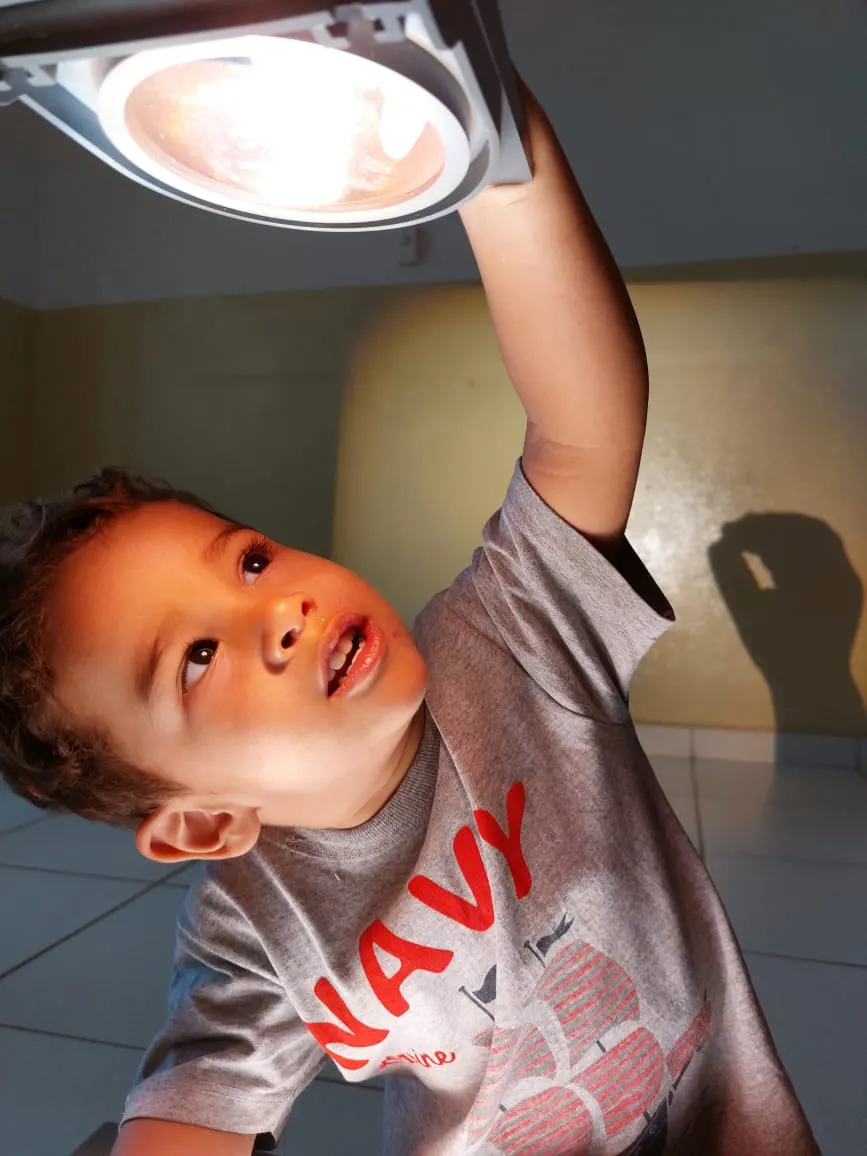 Criança observando de perto a luz de um refletor