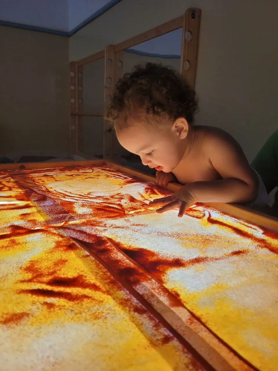 Criança explorando uma mesa de areia iluminada